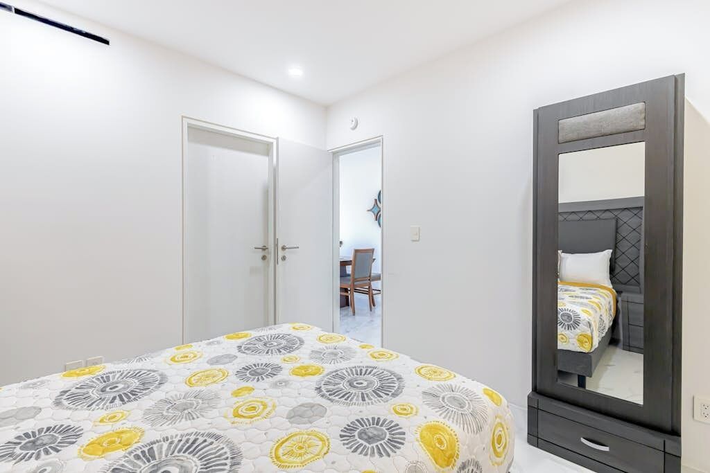 A bedroom with a bed, a wardrobe, and a mirror.