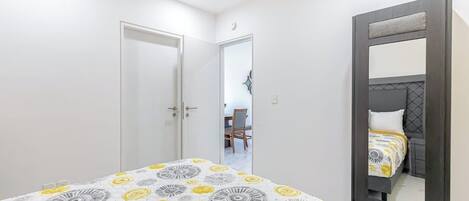 A bedroom with a bed, a wardrobe, and a mirror.