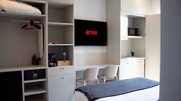 Une chambre d’hôtel moderne équipée d’un lit, d’un téléviseur fixé au mur, d’un bureau avec une chaise et d’une armoire.