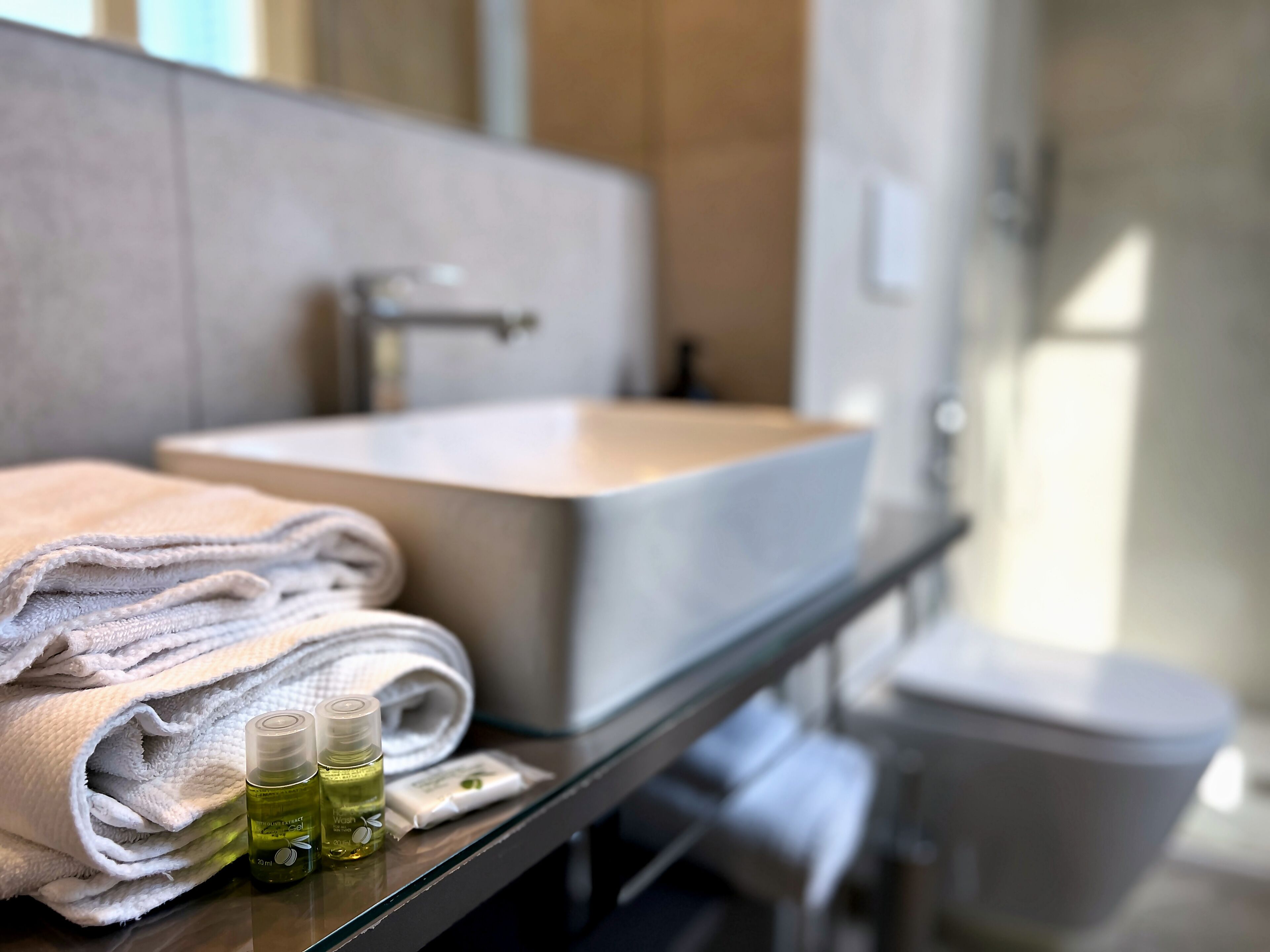 A bathroom with a sink, towels, and toiletries.