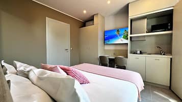 Ein Hotelzimmer mit Bett, Schreibtisch, Fernseher und einer Küchenzeile.