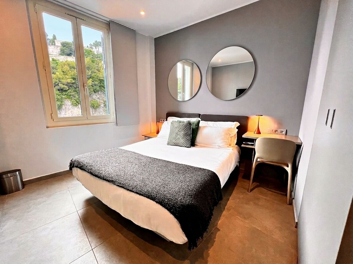 Ein Schlafzimmer mit einem Bett, zwei runden Spiegeln, einem Schreibtisch und einem Stuhl.