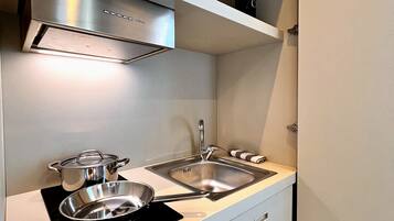 A compact kitchen with a stainless steel stove, two sinks, and a built-in oven.