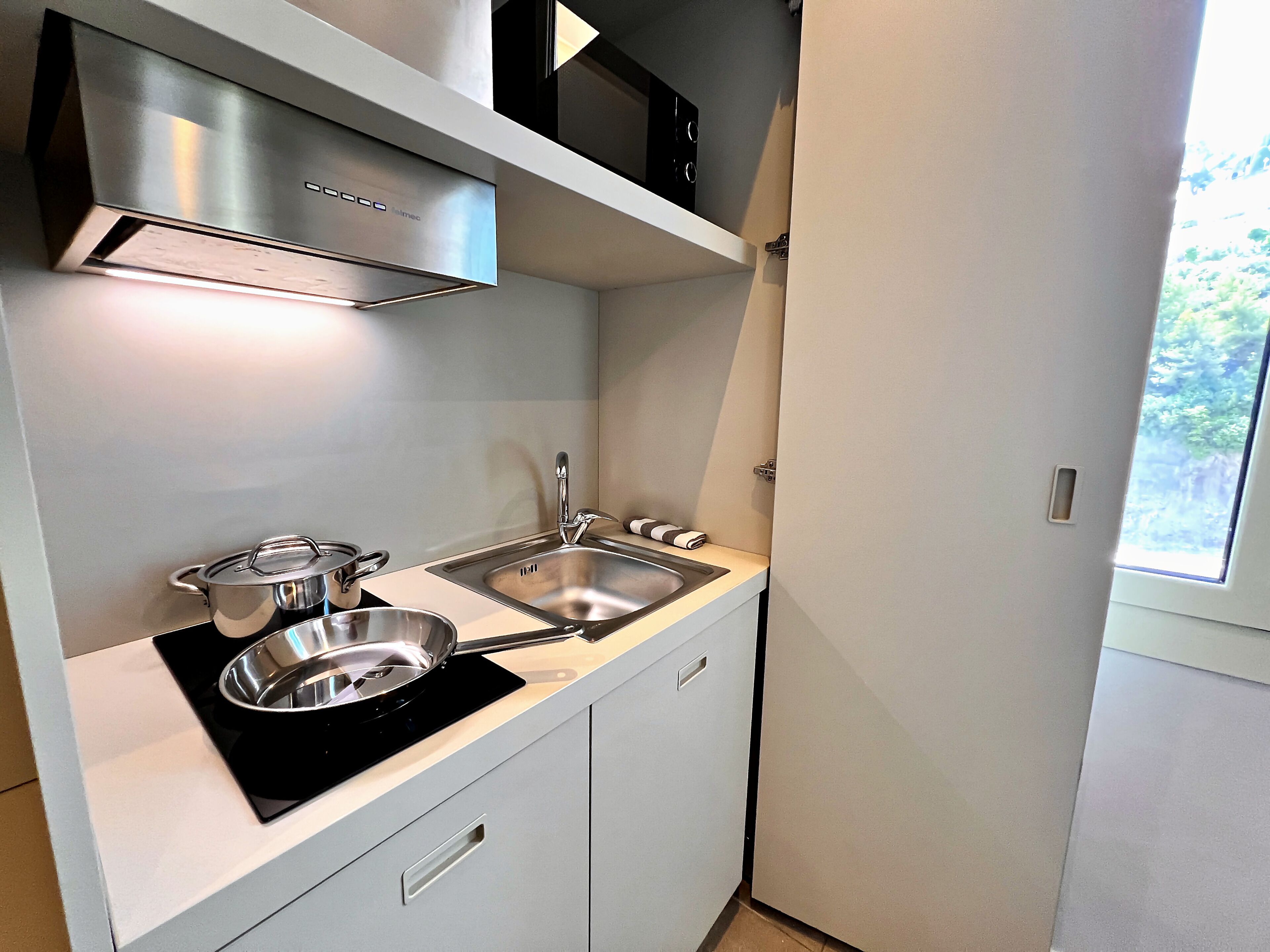 Una cocina moderna con extractor de acero inoxidable, pileta doble y ventana que proporciona luz natural.