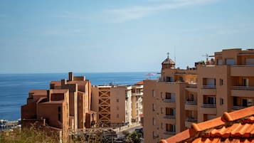 A coastal residential area with buildings, a view of the sea, and a clear sky.