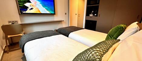 Una habitación de hotel con cama, televisión montada en la pared, escritorio y armario.