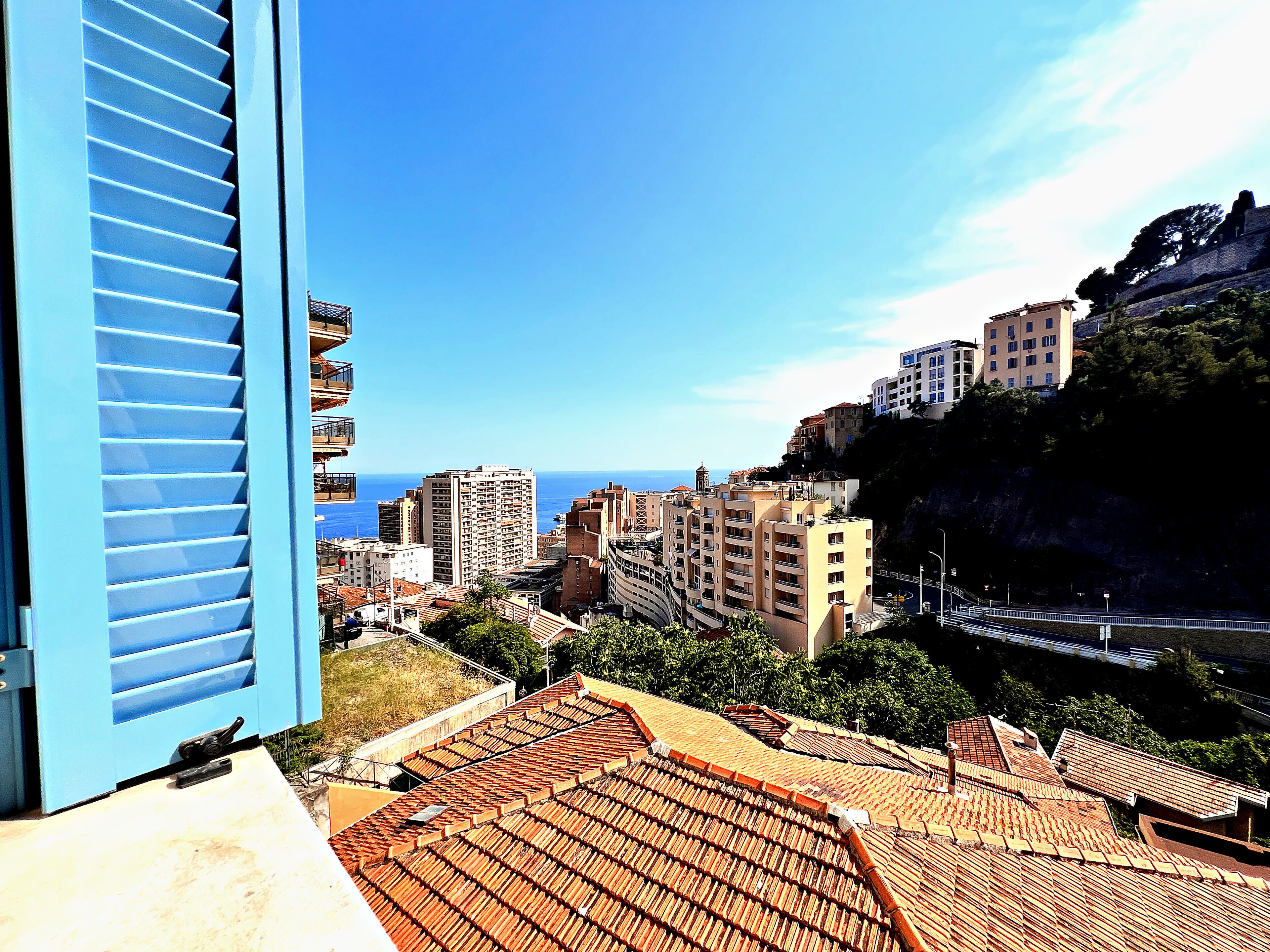Un paisaje urbano costero con edificios, cielo despejado y el mar al fondo.