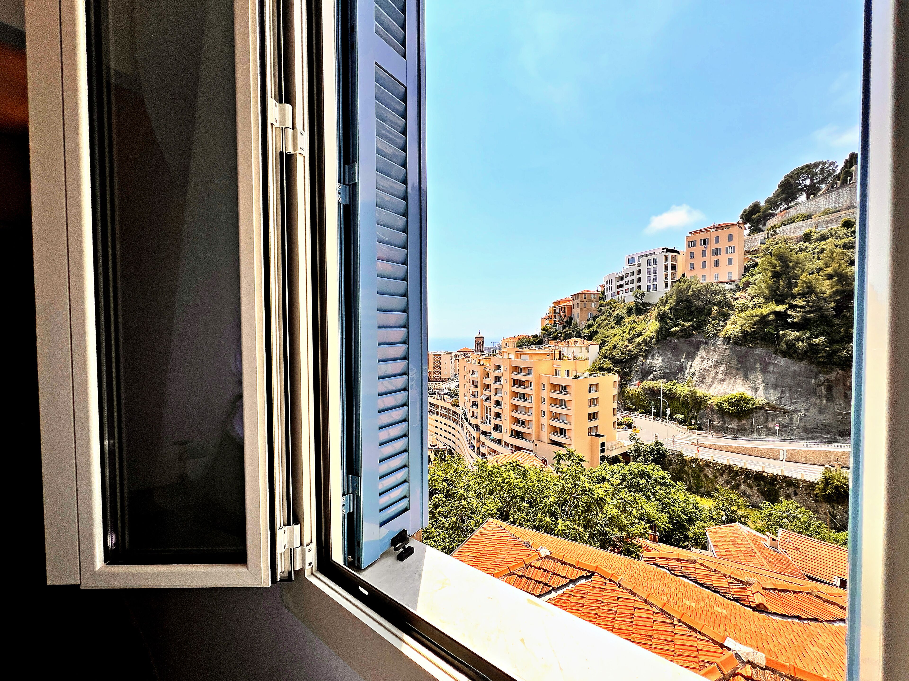 A view through an open window with a building in the background.