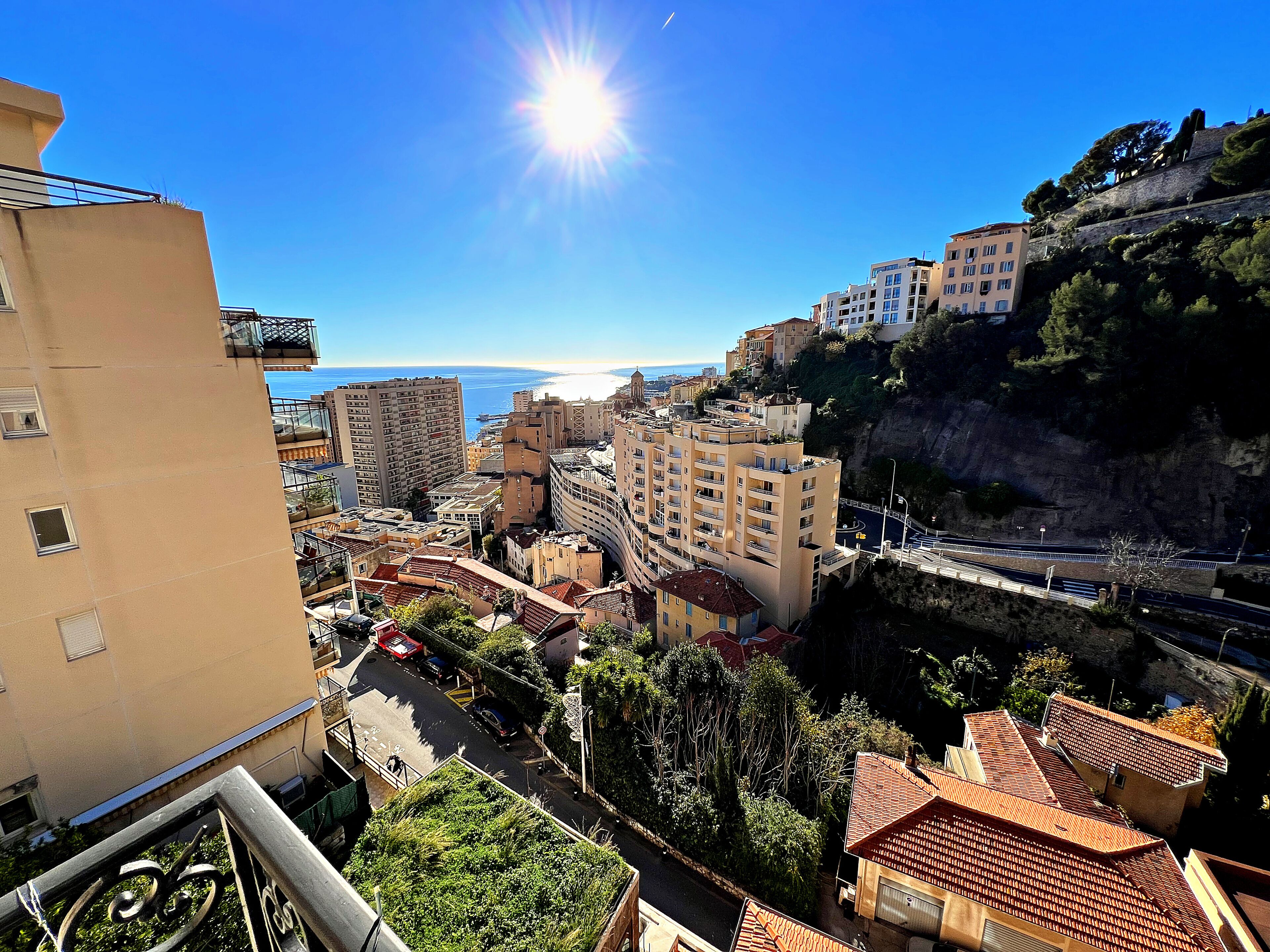 A coastal cityscape with buildings, a clear sky, and a view of the sea.