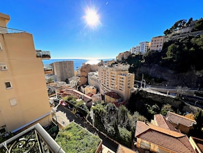 A coastal cityscape with buildings, a clear sky, and a view of the sea.