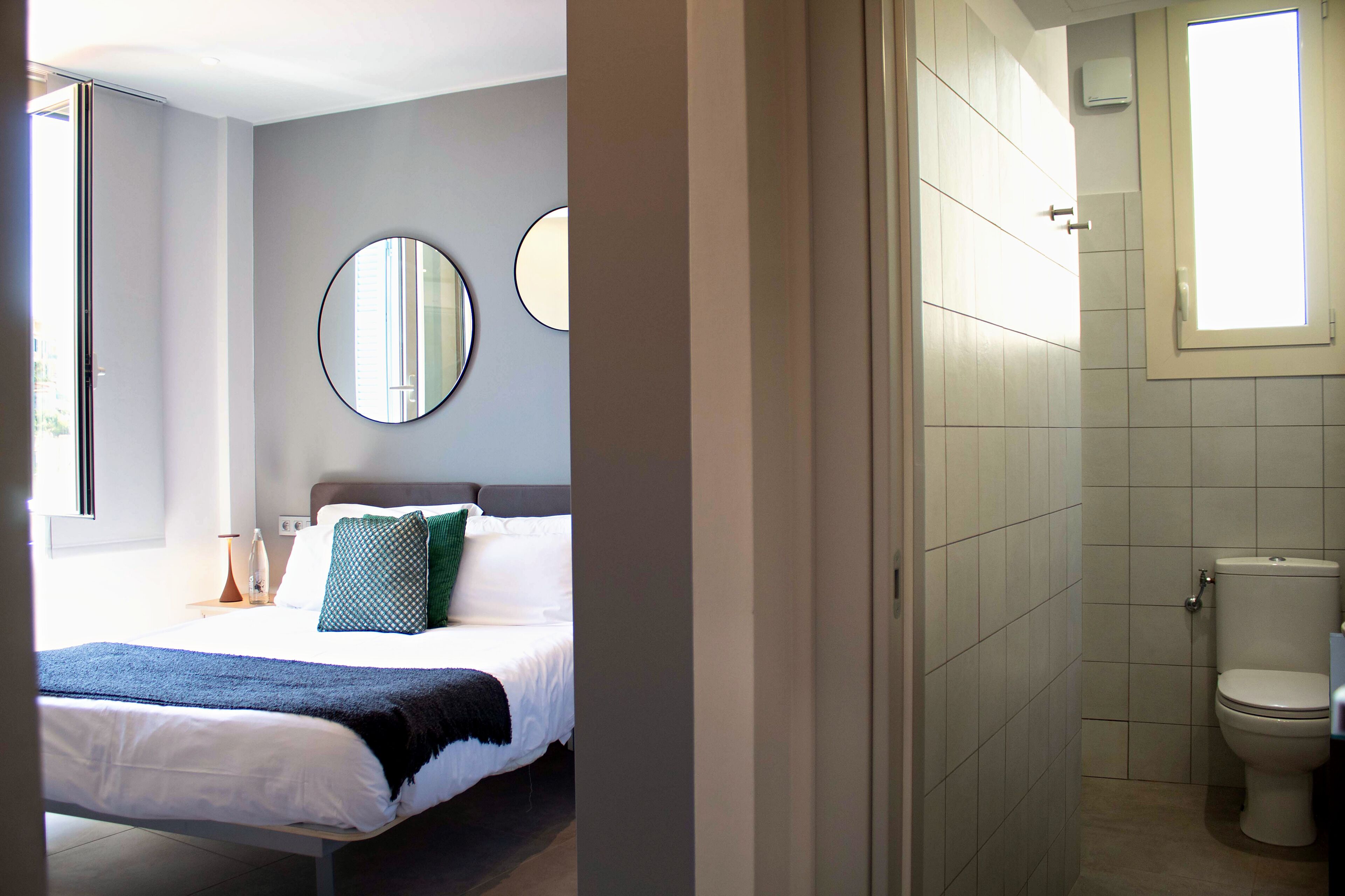 A bedroom with a bed, bedside tables, and a window.