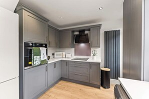 Eine moderne Küche mit grauen Schränken, einem eingebauten Backofen, einer Mikrowelle und einem Toaster.