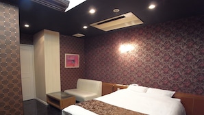 Ein Hotelzimmer mit einem Bett, einem Schlafsofa, einem kleinen Tisch und einer Wand-Klimaanlage.