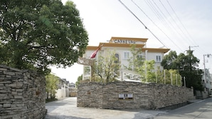 Ein Hotel namens 'Hotel Carnaval' mit einer steinernen Fassade, einer Flagge und blauem Himmel.