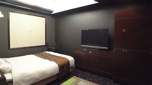 Ein Hotelzimmer mit einem Bett, einem Fernseher, einem Kleiderschrank und einer Deckenleuchte.