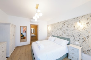 A bedroom with a bed, bedside table, wardrobe, and a mirror.