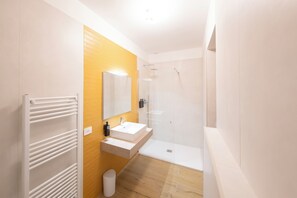 Un bany modern amb un vàter blanc, un mirall i una dutxa.