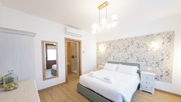 Une chambre à coucher avec un lit, une table de chevet, un miroir et un papier peint à motifs floraux.