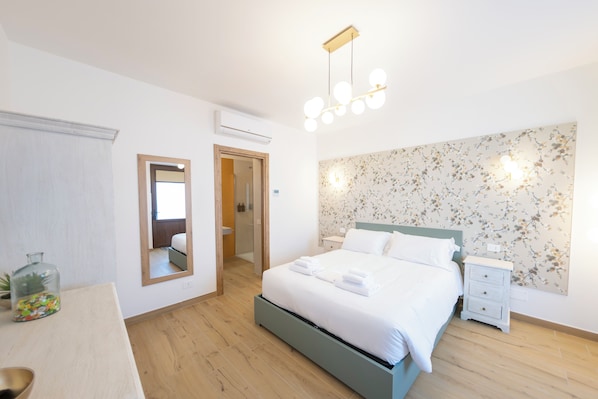 Une chambre à coucher avec un lit, une table de chevet, un miroir et un papier peint à motifs floraux.