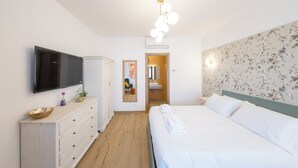 Une chambre d’hôtel avec un lit, une télévision, une commode, un miroir et une porte de salle de bain.