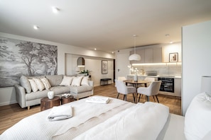 A modern hotel room with a bed, a sofa, a dining table, and a kitchen area. - RentPlanet - Apartamenty Dyrekcyjna (Katowice)