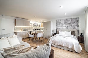 A modern hotel room with a bed, a sofa, a dining area, and a kitchen. - RentPlanet - Apartamenty Dyrekcyjna (Katowice)