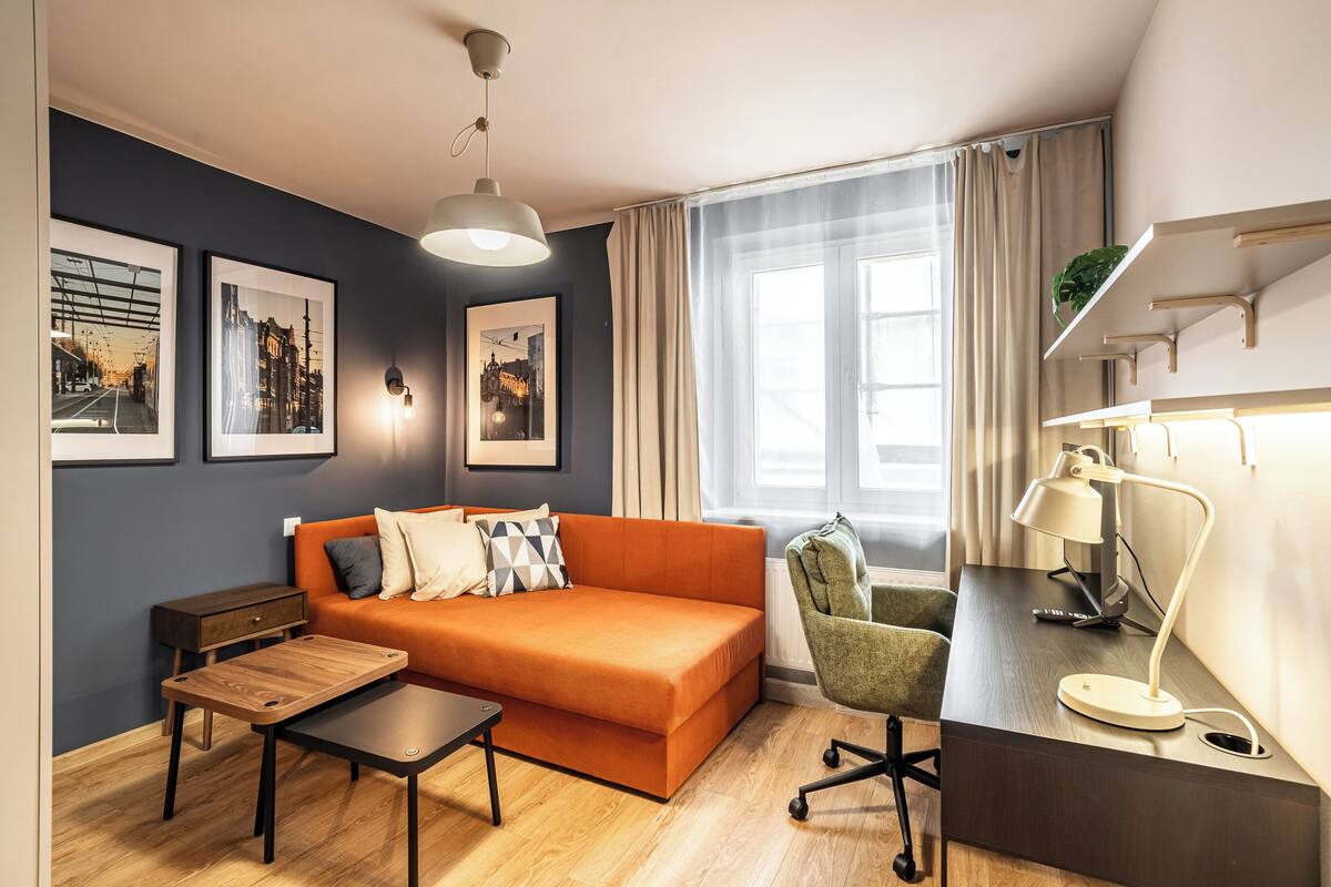 Uma sala de estar moderna com sofá, mesa de centro, escrivaninha, luminária, poltrona e obras de arte nas paredes.