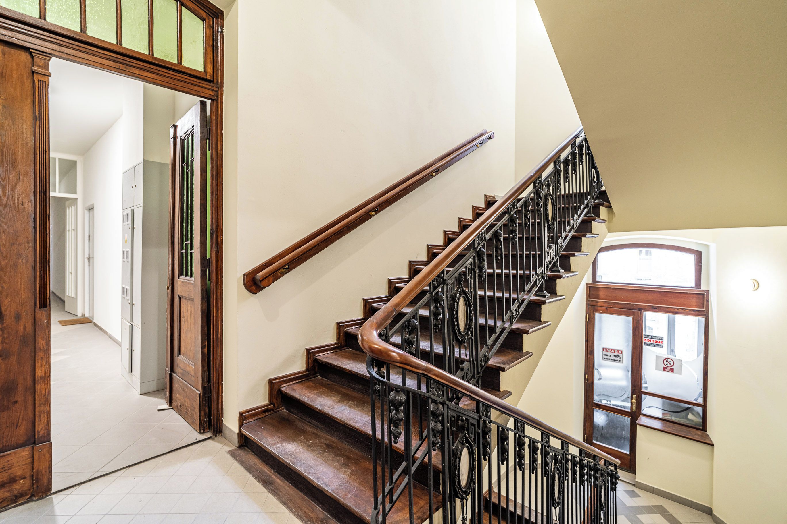 A staircase with wooden steps and black metal railings, leading to an upper floor.