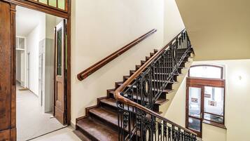 A staircase with wooden steps and black metal railings, leading to an upper floor.