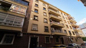 Un immeuble résidentiel à plusieurs étages, doté de balcons, de fenêtres et d’un espace de stationnement.