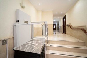 Ein Hotelinnenraum mit Treppe, Geländer und strukturierter Bodenfläche.