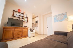 Ein Wohnzimmer mit Fernseher, Holzschrank, weißem Sessel, braunem Sofa und einer Karte an der Wand.