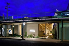 A modern building with a covered entrance, a sign with Japanese characters, and a satellite dish on the roof. - Yuya Tenjin - Hostel (Matsue)