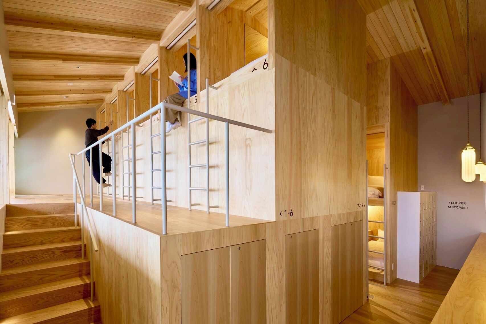 Una escalera de madera con barandilla de metal que lleva a una habitación con una exhibición de maletas.