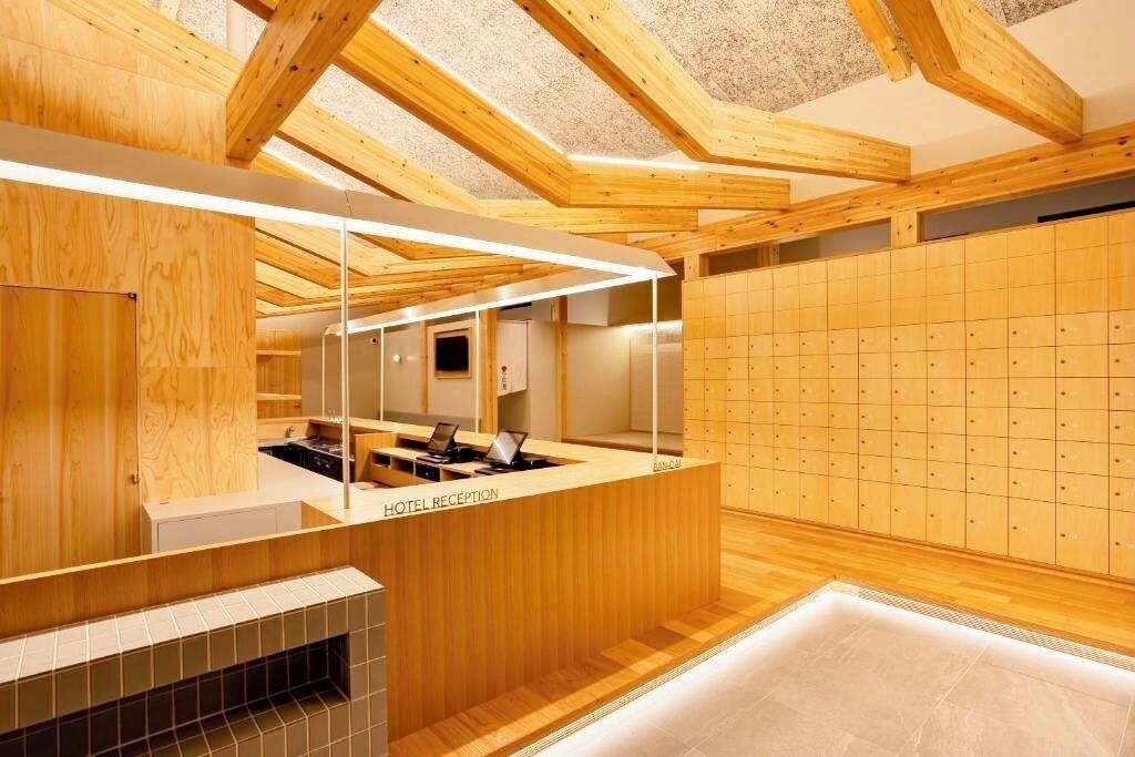 A hotel reception area with a wooden reception desk, a computer, and a tiled floor.