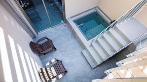 Un área de piscina en la azotea con acceso por puertas de cristal, un jacuzzi y mobiliario exterior.