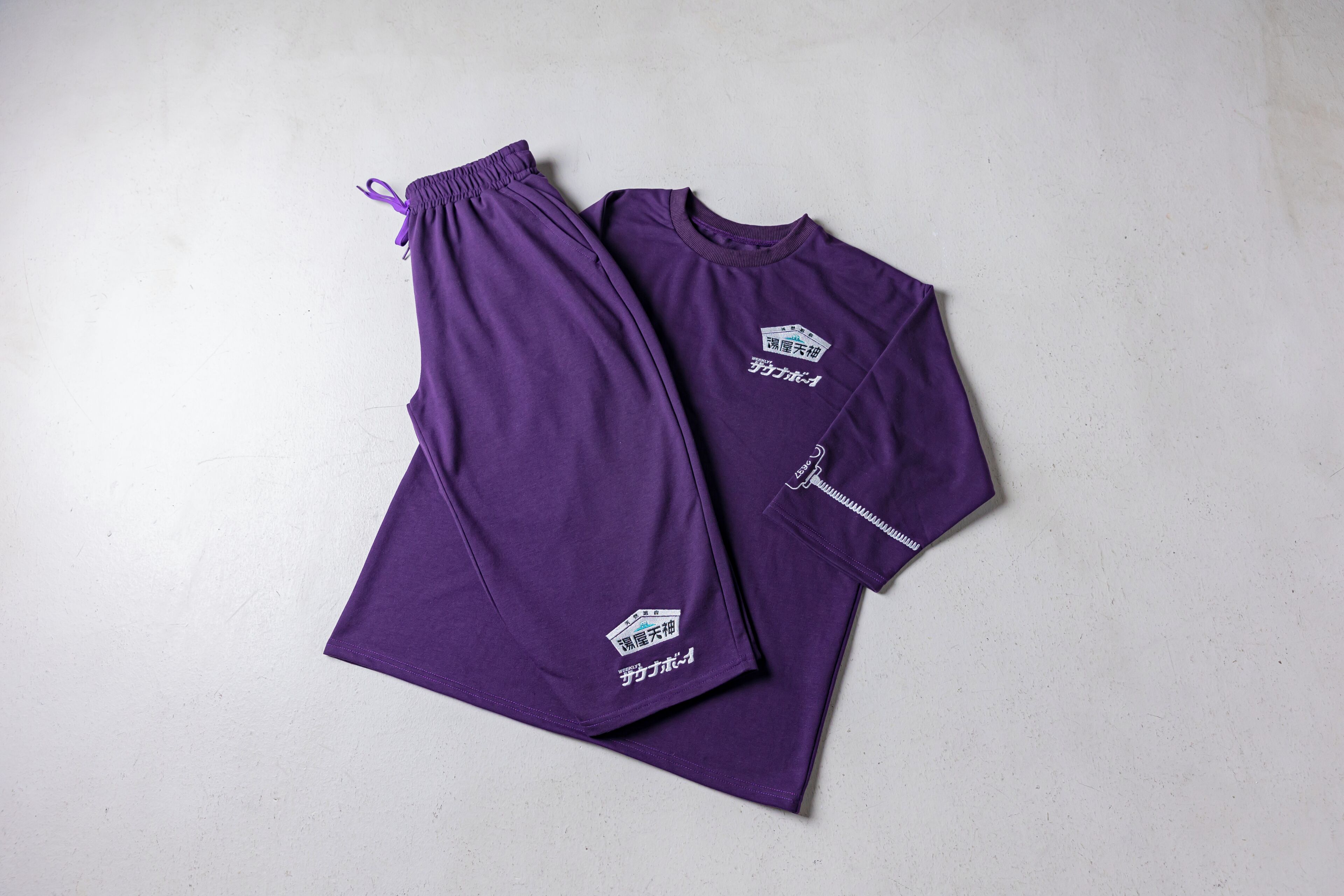 A purple sports outfit with a logo on the chest and a drawstring on the pants.