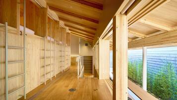 A wooden interior with a central staircase, wooden floors, and a view of greenery outside.