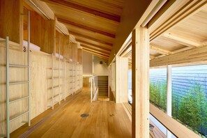 Un interno in legno con una scala centrale, parquet e vista su spazi verdi.