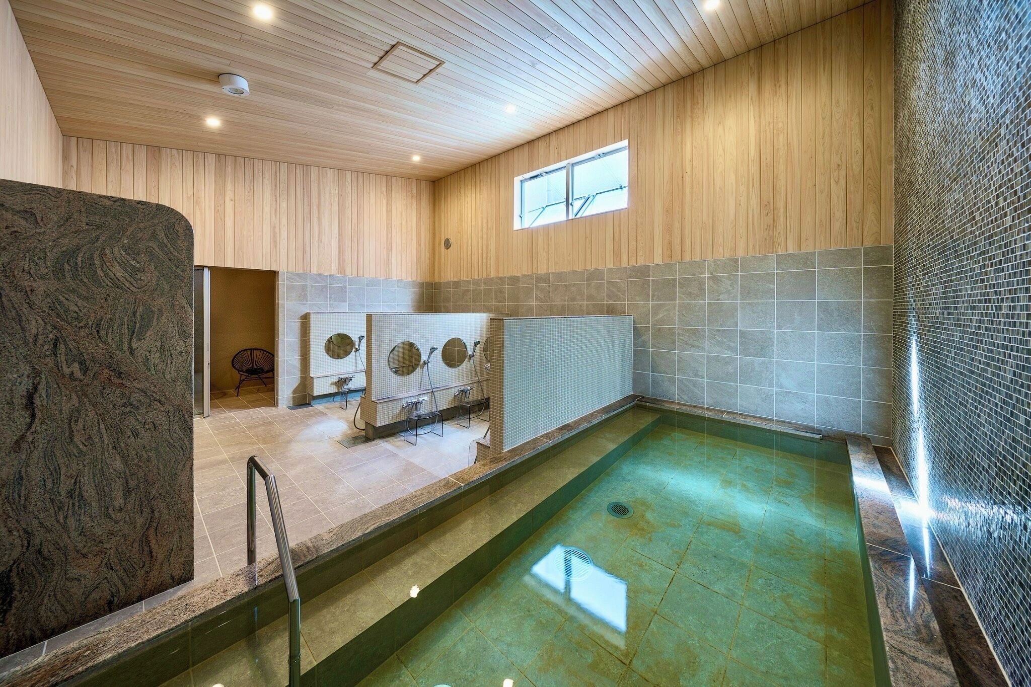 Ein moderner, überdachter Pool mit Holzbalkendecke und Fliesenwänden.