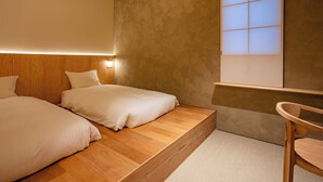 Un dormitorio con dos camas, cabeceros de madera, una mesita de noche y una ventana con vistas.
