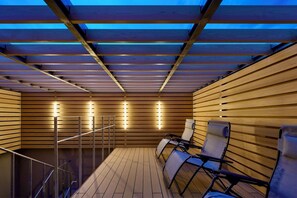 A wooden deck with a glass ceiling, metal railings, and seating. - Yuya Tenjin - Hostel (Matsue)