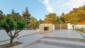 Un patio con chimenea de piedra, escalones y una entrada con reja.
