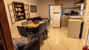 Una cocina compacta con una mesa de comedor, sillas, un refrigerador y una cafetera.