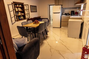 A compact kitchen with a dining table, chairs, a refrigerator, and a coffee maker. - Aroma Zia_Mint Residence  offers a slower, more authentic way to experience Kos! (Lagoudi Zia)