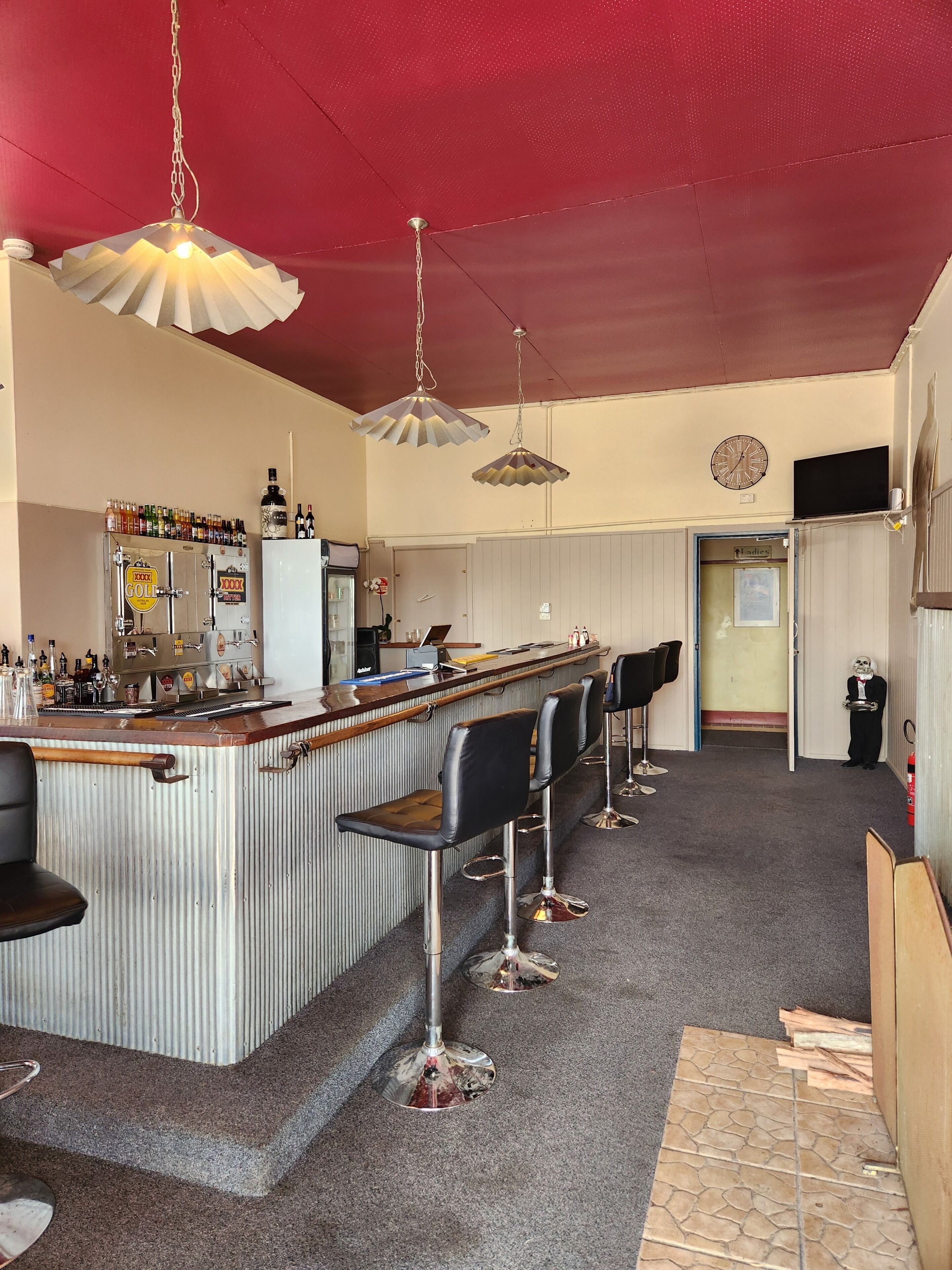A bar area with a counter, stools, and hanging lights.