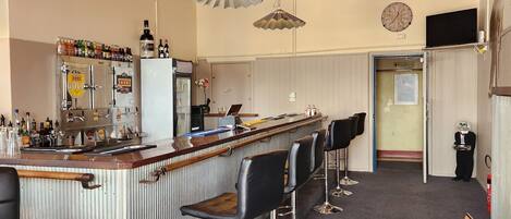 A bar area with a counter, stools, and hanging lights.
