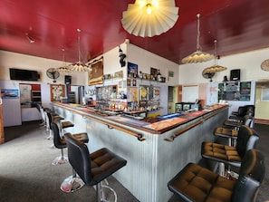A bar area with a counter, stools, and various bottles. - Hotel Cecil Wondai (Wondai)