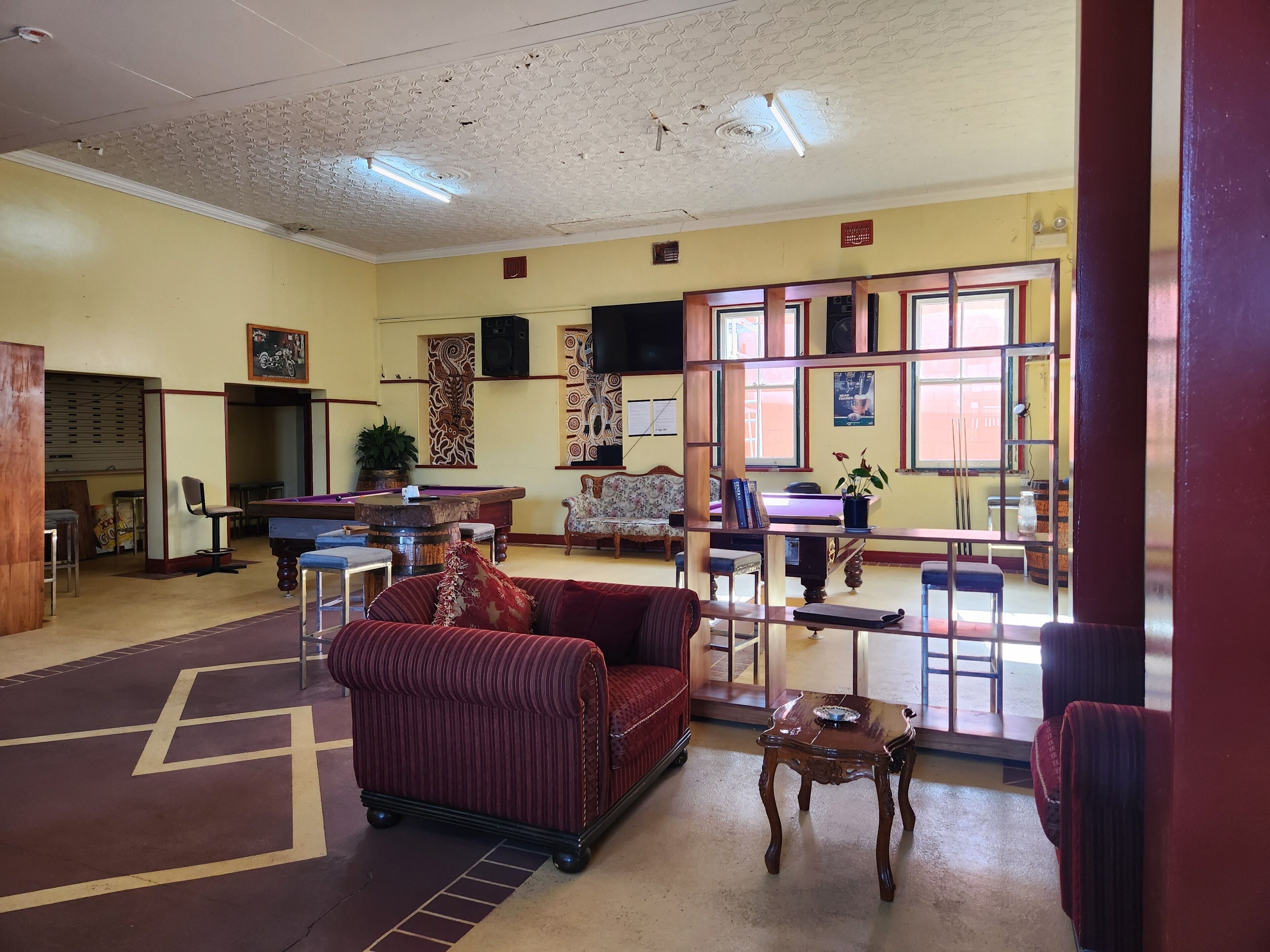 A billiards room with a pool table, a red sofa, and a small table with a plate.