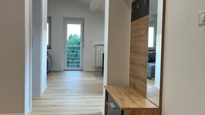A modern interior with a wooden floor, a built-in bench, and a large mirror. - Charming Alpine Apartment with Sauna (Kobarid)